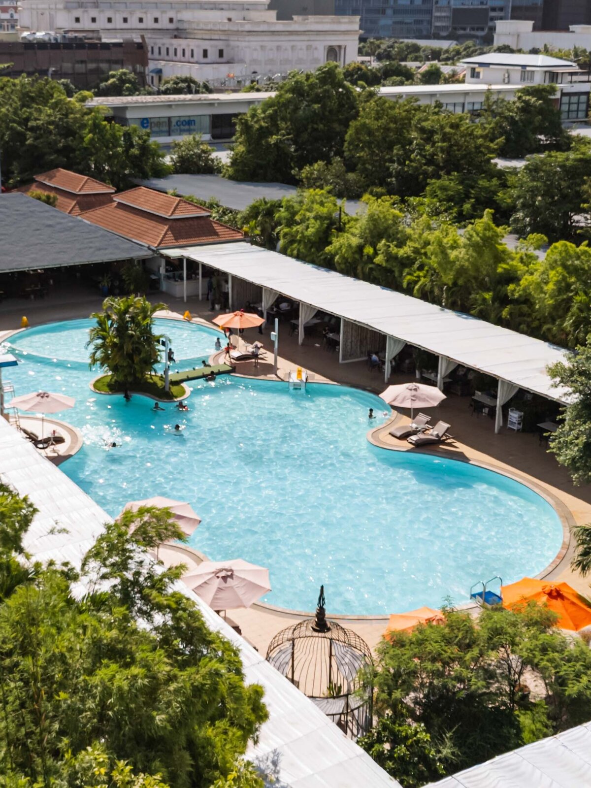 Aerial view of a large outdoor of DIB Club swimming pool surrounded by tropical trees in Phnom Penh