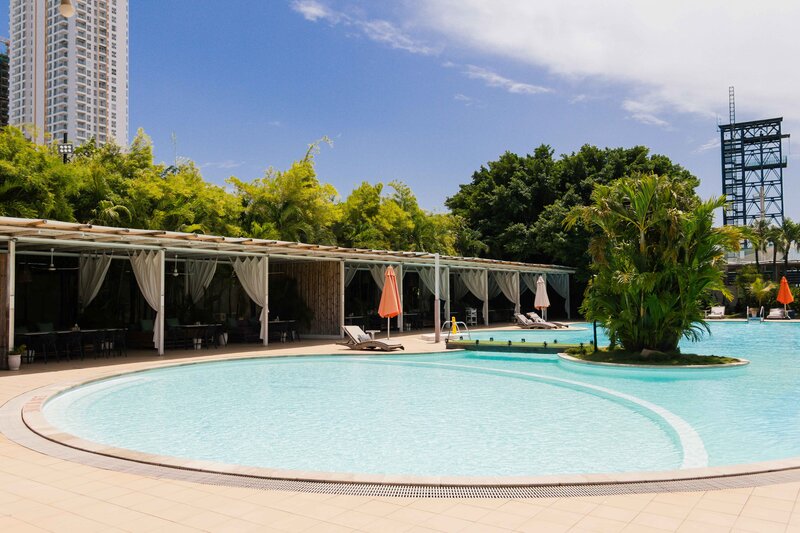 Wide shot of the pool shallow entry area next to covered seating and palm trees