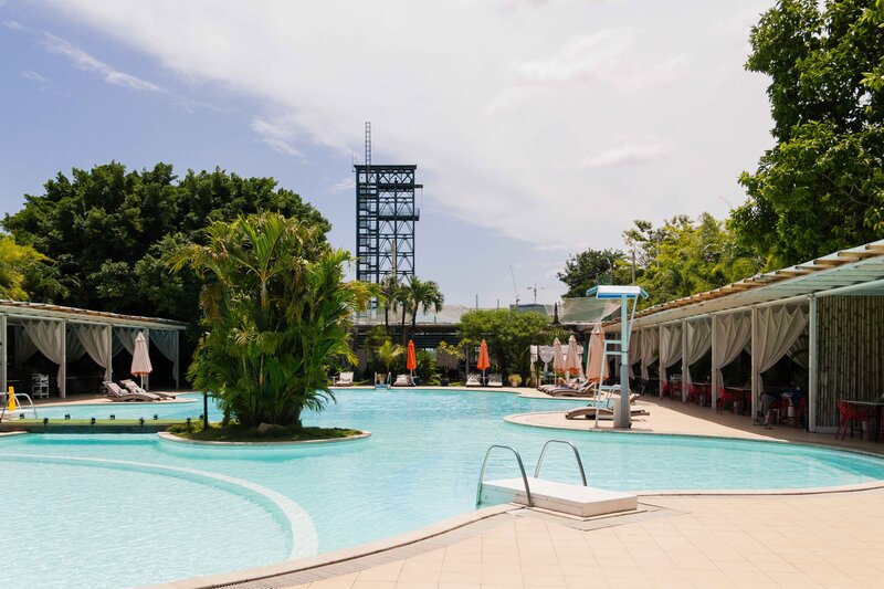 Ground-level view of the swimming pool area with white cabanas and umbrellas