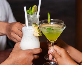 Guests clinking various colourful cocktails including a Piña Colada and a green martini at Island Center Point hotel, Koh Rong Sanloem.