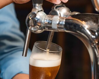 Bartender pulling a tap handle to pour a chilled craft beer at the Beach Bar at Island Center Point hotel, Koh Rong Sanloem.