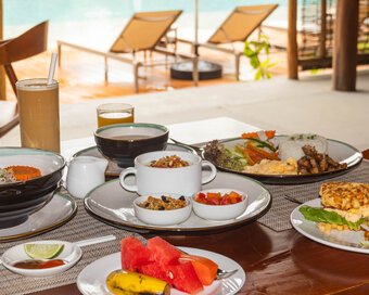 Table filled with Asian and Western breakfast options with a view of swimming pool at Island Center Point hotel, Koh Rong Sanloem.