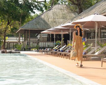 Island-goer in a woven dress and sun hat strolling along the pool deck at Island Center Point, Koh Rong Sanloem.