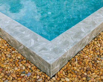 Golden pebbles up to the sleek tile border of the crystal-clear pool at Island Center Point hotel, Koh Rong Sanloem.