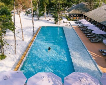 High-angle shot of an island-goer enjoying a swim in the long pool, with an open-air restaurant on the side at Island Center Point hotel, Koh Rong Sanloem.