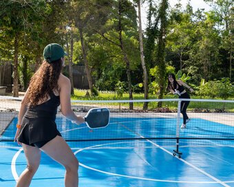 Players engaged in a pickleball match surrounded by lush trees at Island Center Point hotel, Koh Rong Sanloem.