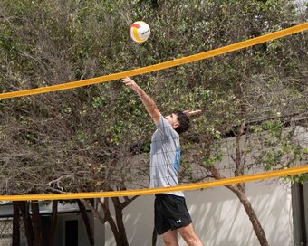 Energetic island-goer jumping into the air for a volleyball serve on the soft white sand at Island Center Point hotel, Koh Rong Sanloem.