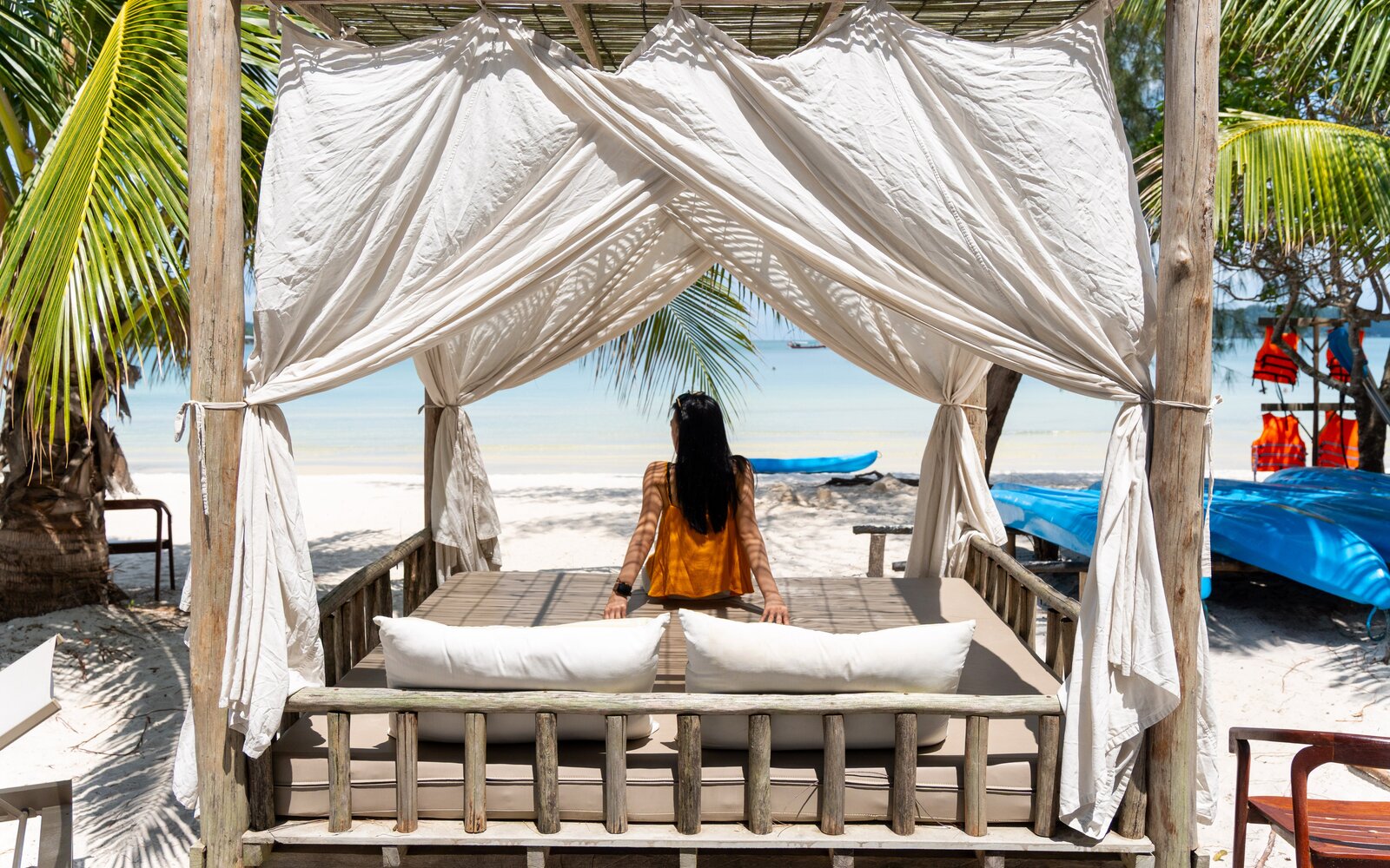 Island seeker relaxing inside a shaded wooden beach cabana looking out toward the ocean in Koh Rong Sanloem.