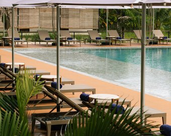 Row of sun loungers under white umbrellas lined up along the swimming pool of Island Center Point, Koh Rong Sanloem