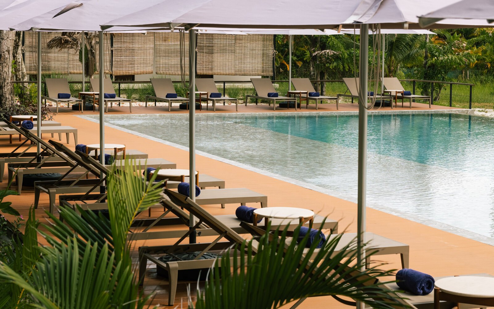 Row of sun loungers under white umbrellas lined up along the swimming pool of Island Center Point, Koh Rong Sanloem