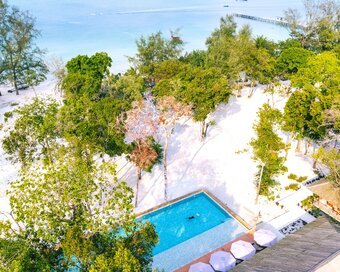 Aerial view of a large swimming pool surrounded by white sand and lush trees at Island Center Point.