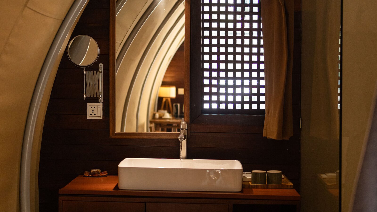 Rectangular ceramic vessel sink set on a dark wooden vanity counter under a large wood-framed mirror.