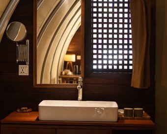 Rectangular ceramic vessel sink set on a dark wooden vanity counter under a large wood-framed mirror.
