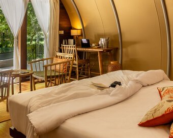 Warm tone bedroom layout with bamboo chairs and open doors leading out to the designer plunge pool.