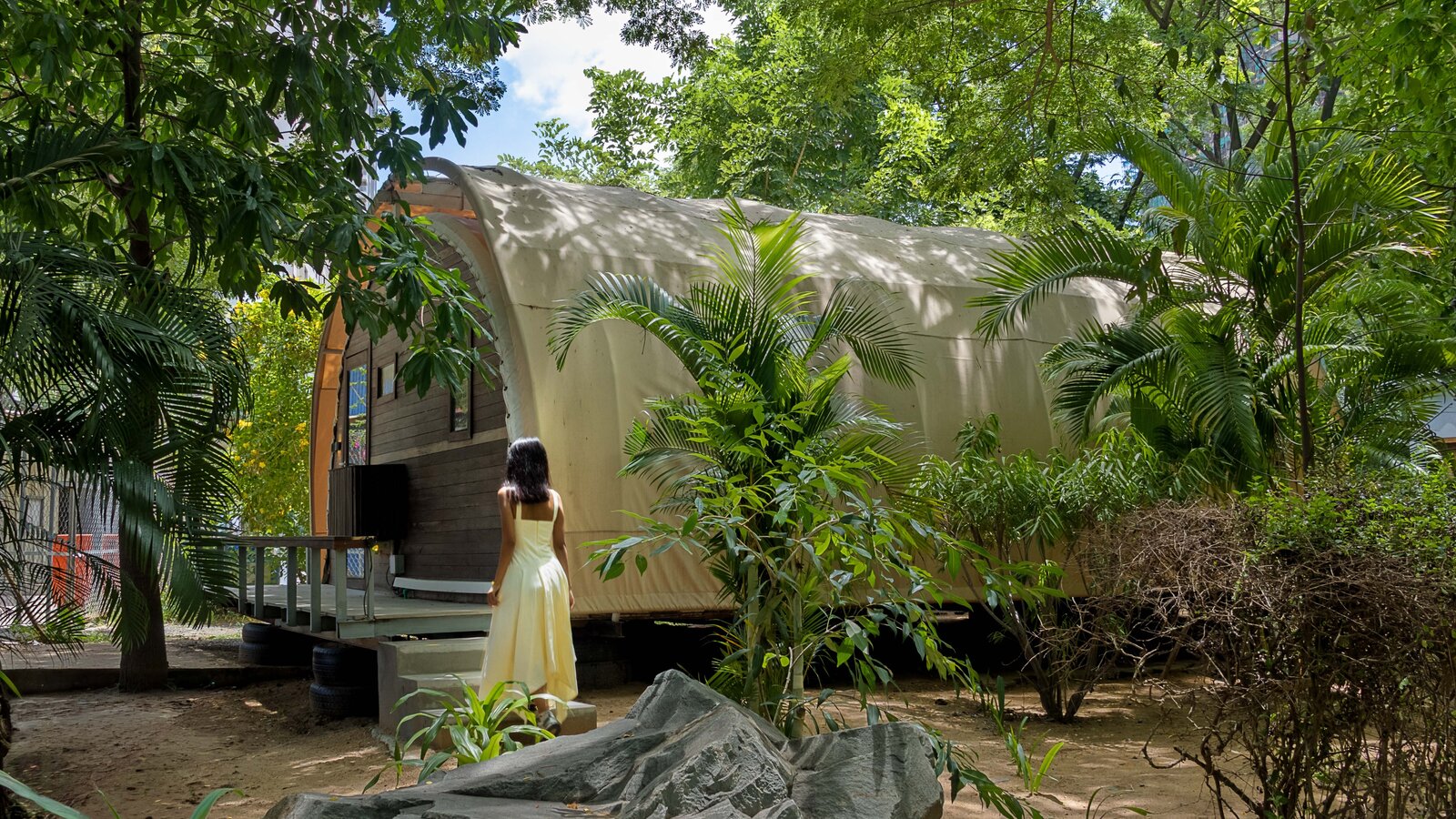 Guest walking toward the tented-bungalow surrounded by green gardens.