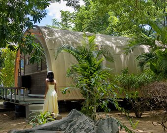 Guest walking toward the tented-bungalow surrounded by green gardens.