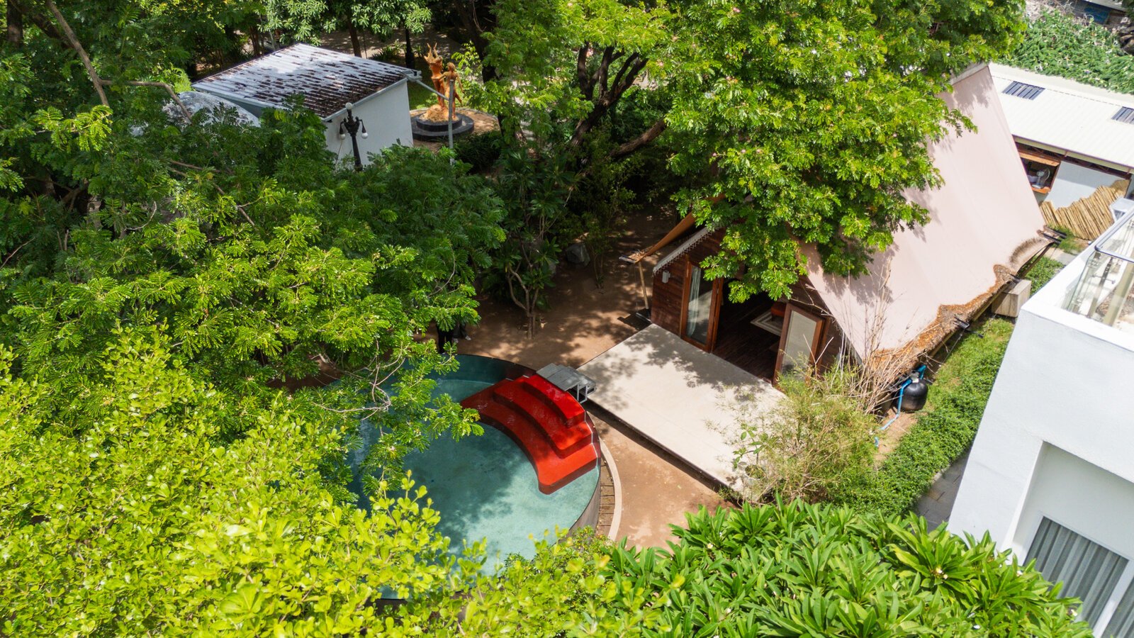 Aerial view of wood-and-bamboo hideaway with a designer plunge pool under the tree canopy.