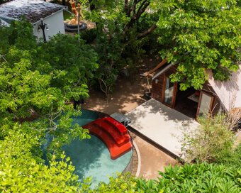Aerial view of wood-and-bamboo hideaway with a designer plunge pool under the tree canopy.