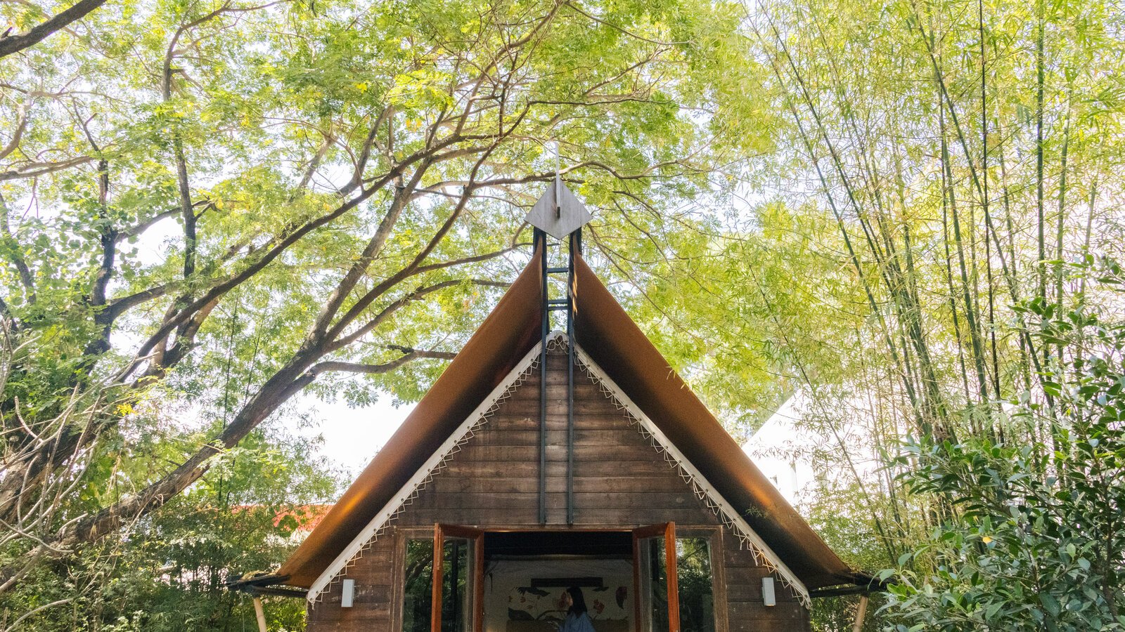 Double-layered bamboo and wood sanctuary nestled under a sunlit forest canopy.