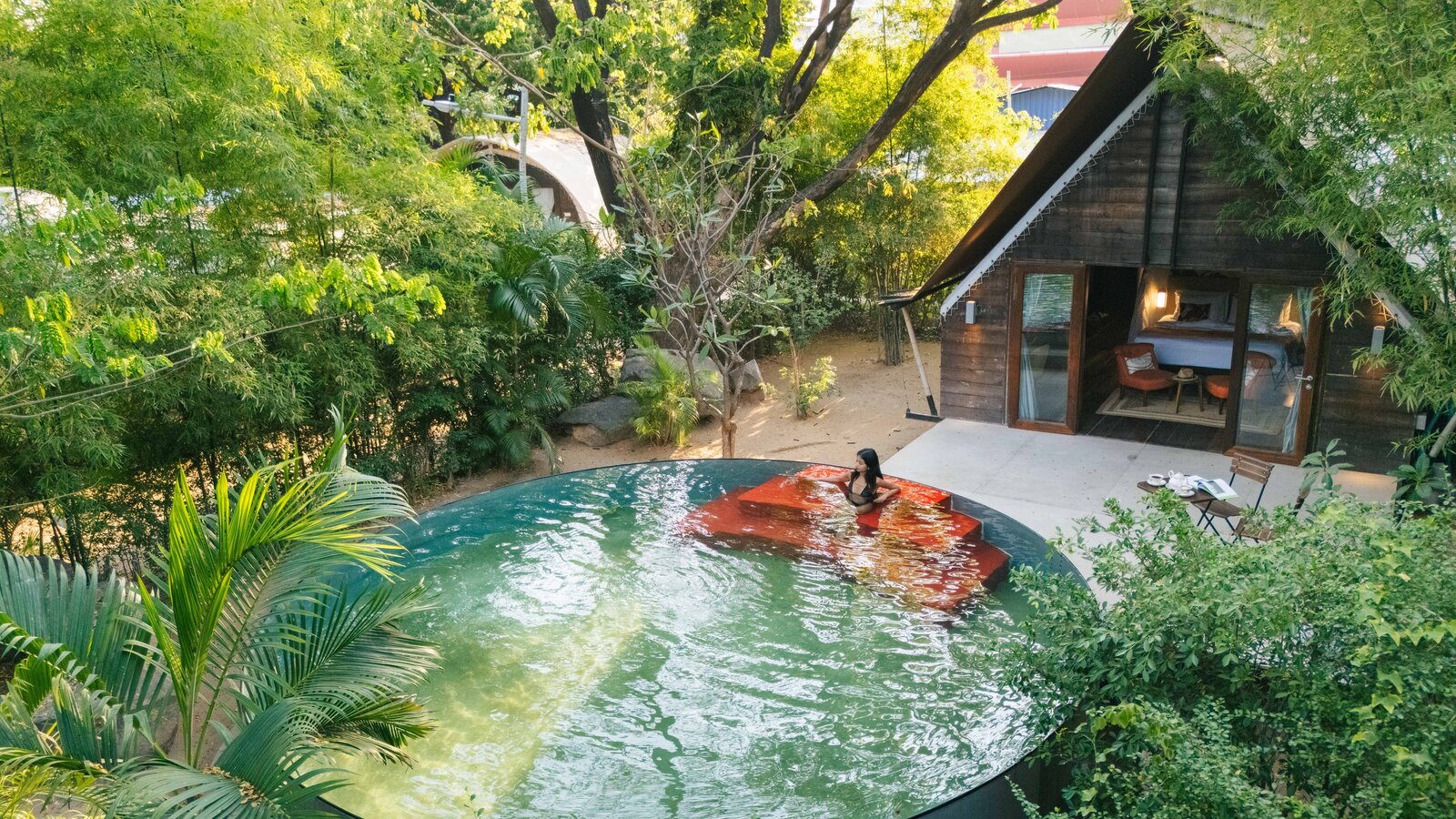 Steel-and-wood jungle hideaway centered around red-stepped circular pool.