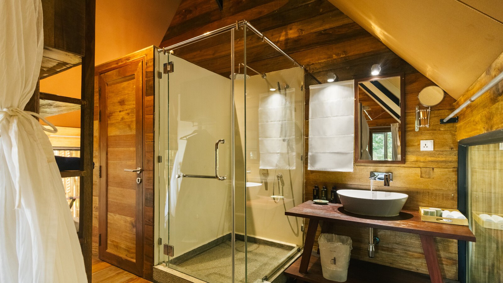 Glass-enclosed shower set inside wood bathroom suite.