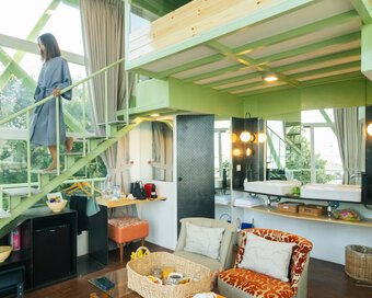 Lving space inside the water tower showing stairs to the loft bedroom and a guest in a blue robe walking down.