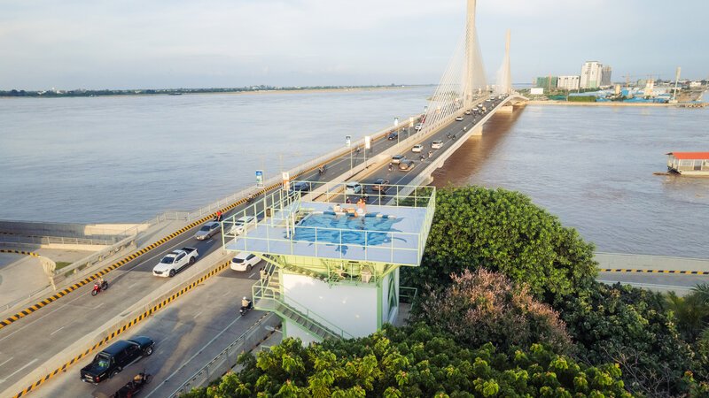 Aerial view of a water tower with a rooftop pool next to a large bridge over a river.