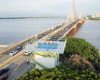 Aerial view of a water tower with a rooftop pool next to a large bridge over a river.