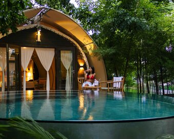 Evening view of Jungloo unit, reflecting on the surface of its private plunge pool, with a person seated on the deck.