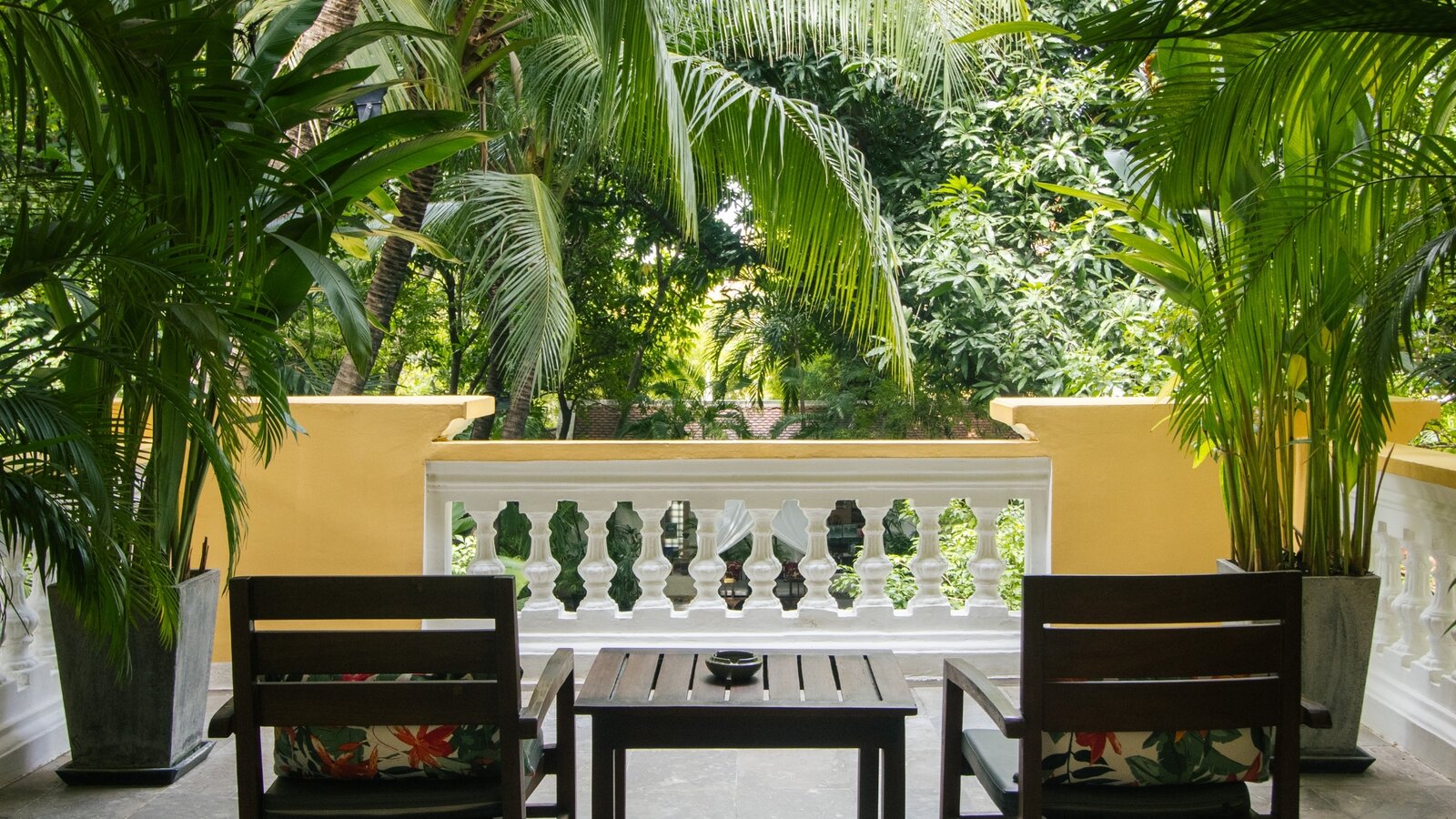 Private balcony with two chairs overlooking the lush gardens from a Deluxe Double room at Pavilion Phnom Penh