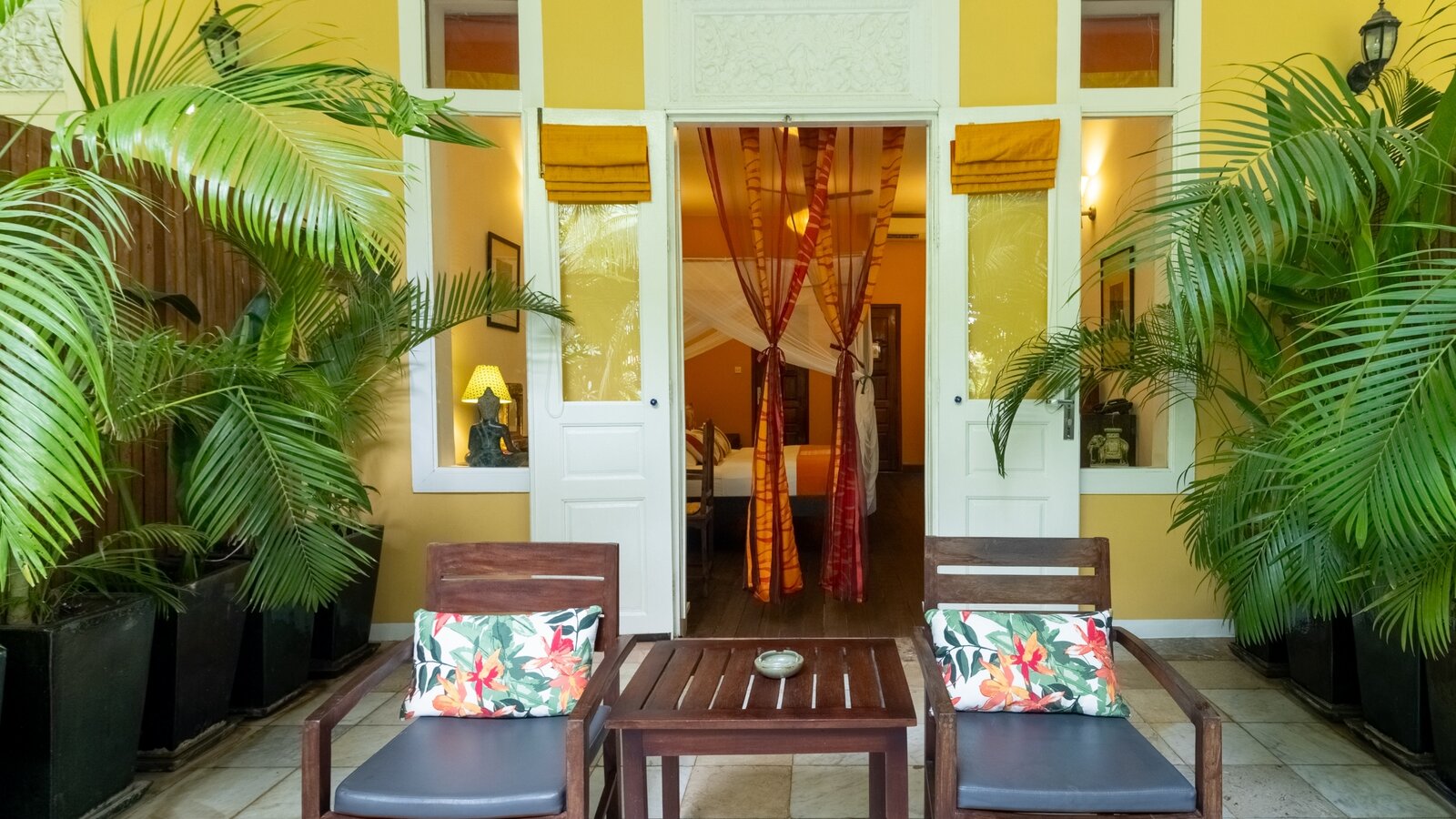Room terrace with seating and tropical plants outside the Deluxe Double room at Pavilion Phnom Penh