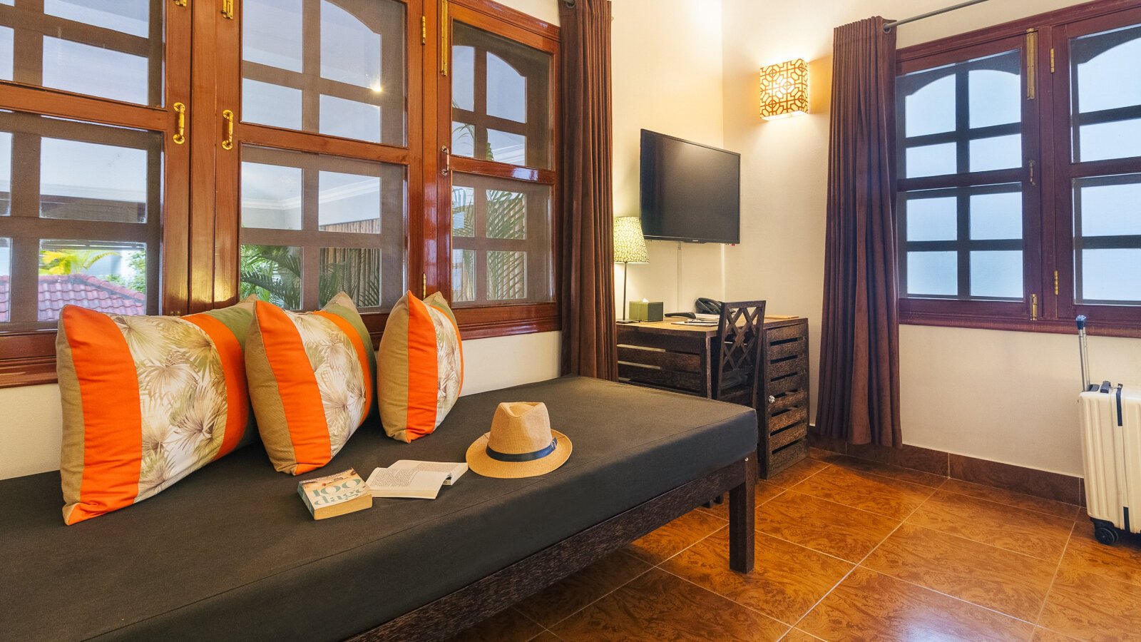 Deluxe Double seating area with daybed, work desk and television at Pavilion Phnom Penh