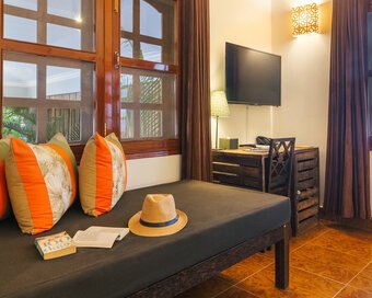 Deluxe Double seating area with daybed, work desk and television at Pavilion Phnom Penh