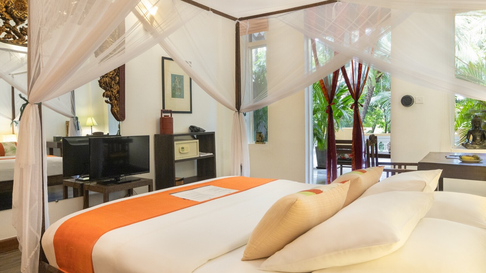 Double Deluxe Room with queen bed, mosquito net and doors opening toward the garden view at Pavilion Hotel, Phnom Penh