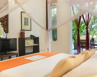 Double Deluxe Room with queen bed, mosquito net and doors opening toward the garden view at Pavilion Hotel, Phnom Penh