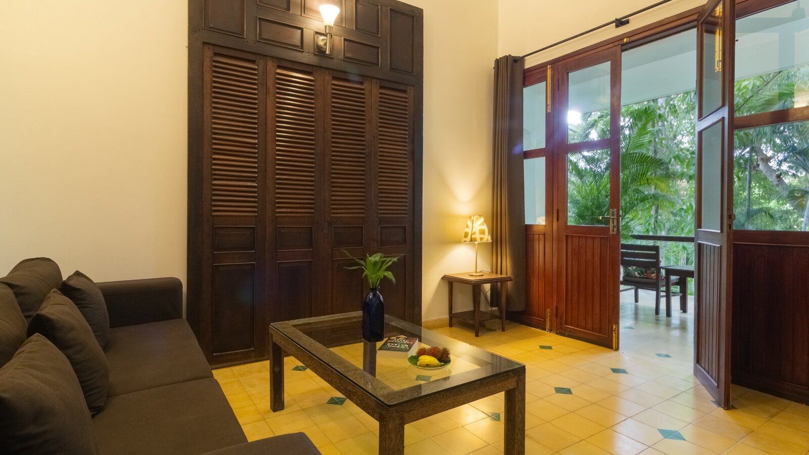 Pavilion Suite living room with sofa, wooden furniture and open doors leading to a private balcony