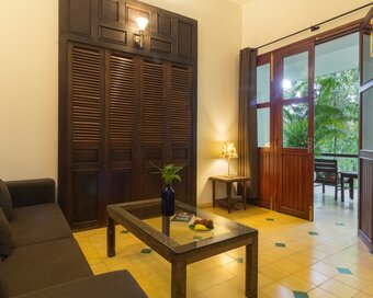 Pavilion Suite living room with sofa, wooden furniture and open doors leading to a private balcony