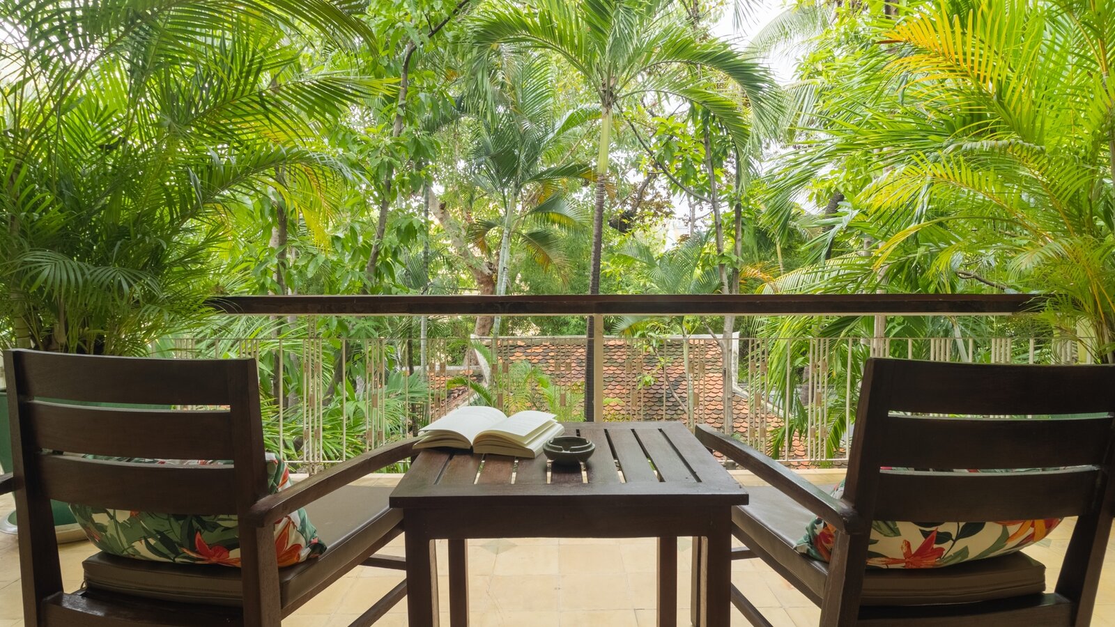 Private balcony with two chairs, table and tropical garden view at Pavilion in Phnom Penh