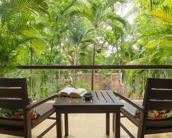 Private balcony with two chairs, table and tropical garden view at Pavilion in Phnom Penh