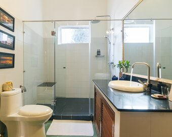 Pavilion suite bathroom with vanity, toilet and glass-enclosed walk-in shower in Phnom Penh