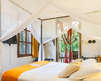 Superior Room with king bed, mosquito net and private balcony with the garden view at Pavilion Phnom Penh