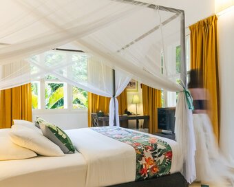 King bed with mosquito net and garden-facing windows in a Superior Double Room at Pavilion Phnom Penh