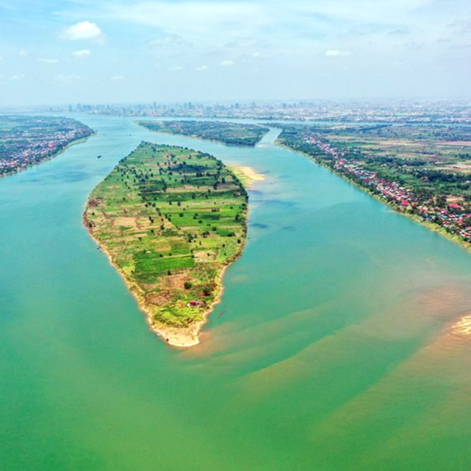 A river island of farmland and scattered homes sits between broad waterways in Phnom Penh.