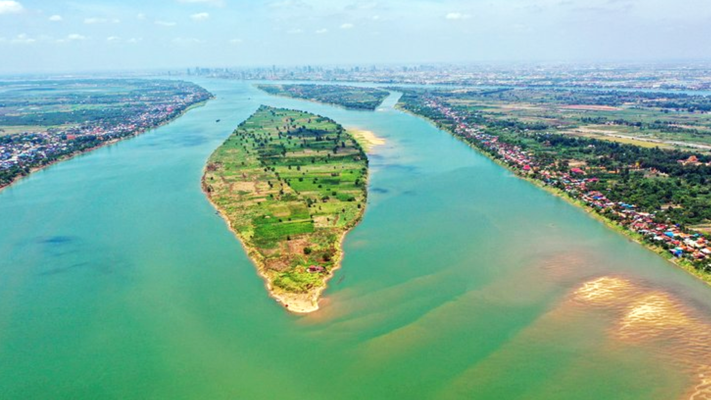 A river island of farmland and scattered homes sits between broad waterways in Phnom Penh.