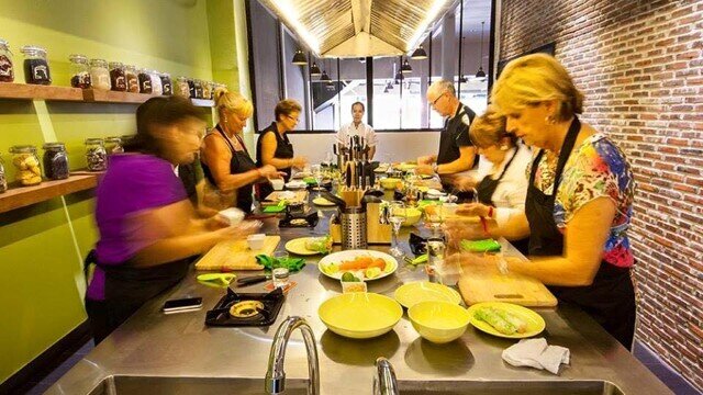 Participants prepare ingredients around a communal kitchen station during a hands-on Khmer cooking class.