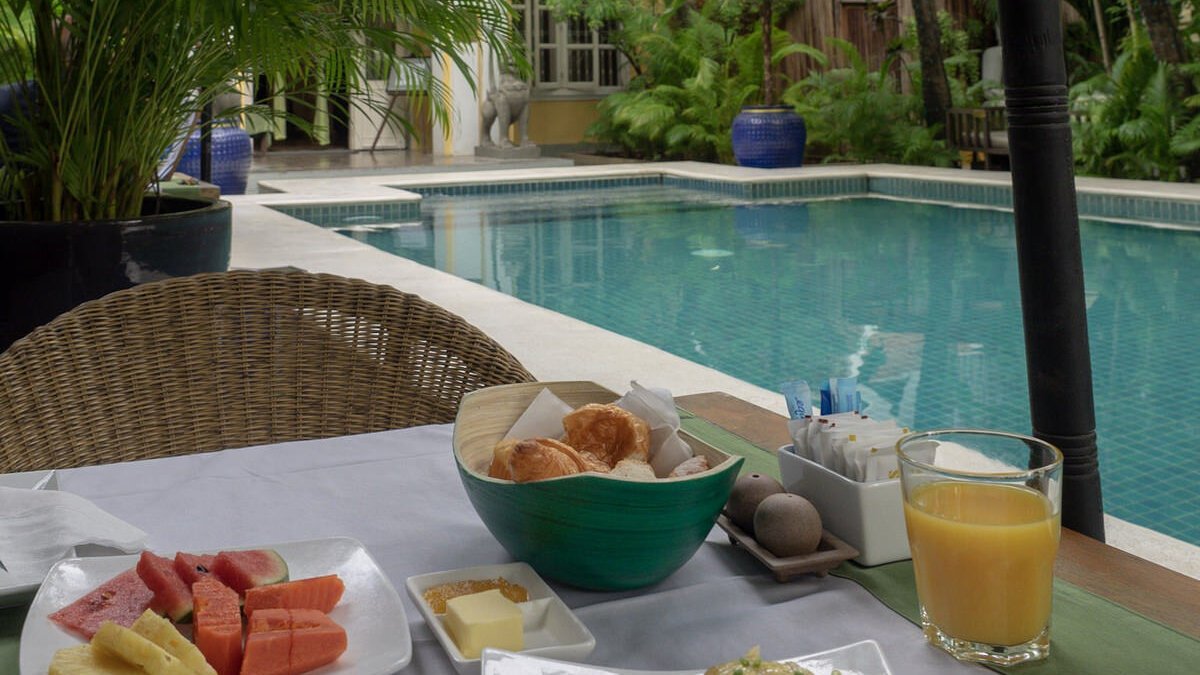 Breakfast spread with fruit, pastries and juice served beside the pool.