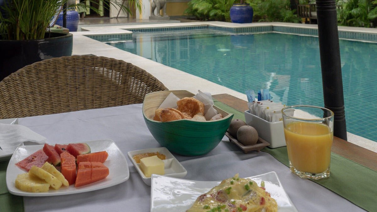 Breakfast spread with fruit, pastries and juice served beside the pool.