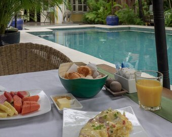 Breakfast spread with fruit, pastries and juice served beside the pool.