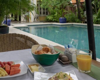 Breakfast spread with fruit, pastries and juice served beside the pool.