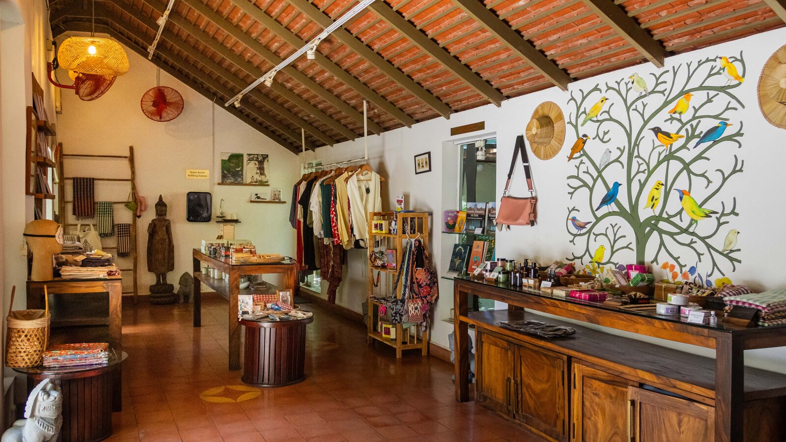 Shop interior featuring artisan goods, textiles, accessories and a bird mural along one wall.